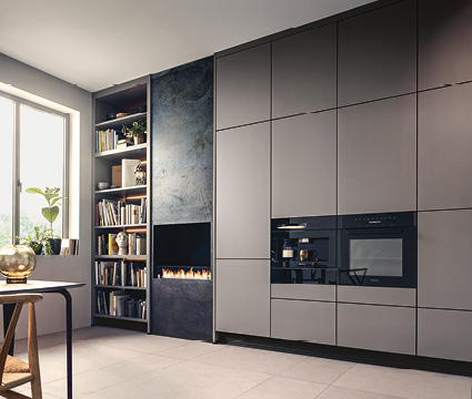 Next125 bei Himmlisch Wohnen Hochschrankwand mit Einbaugeräten neben Regal und modernem Kamin im Wohnraum