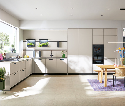 Next125 bei Himmlisch Wohnen Helle Wohnküche mit L-förmiger Einbauküche, Esstisch und großen Fenstern