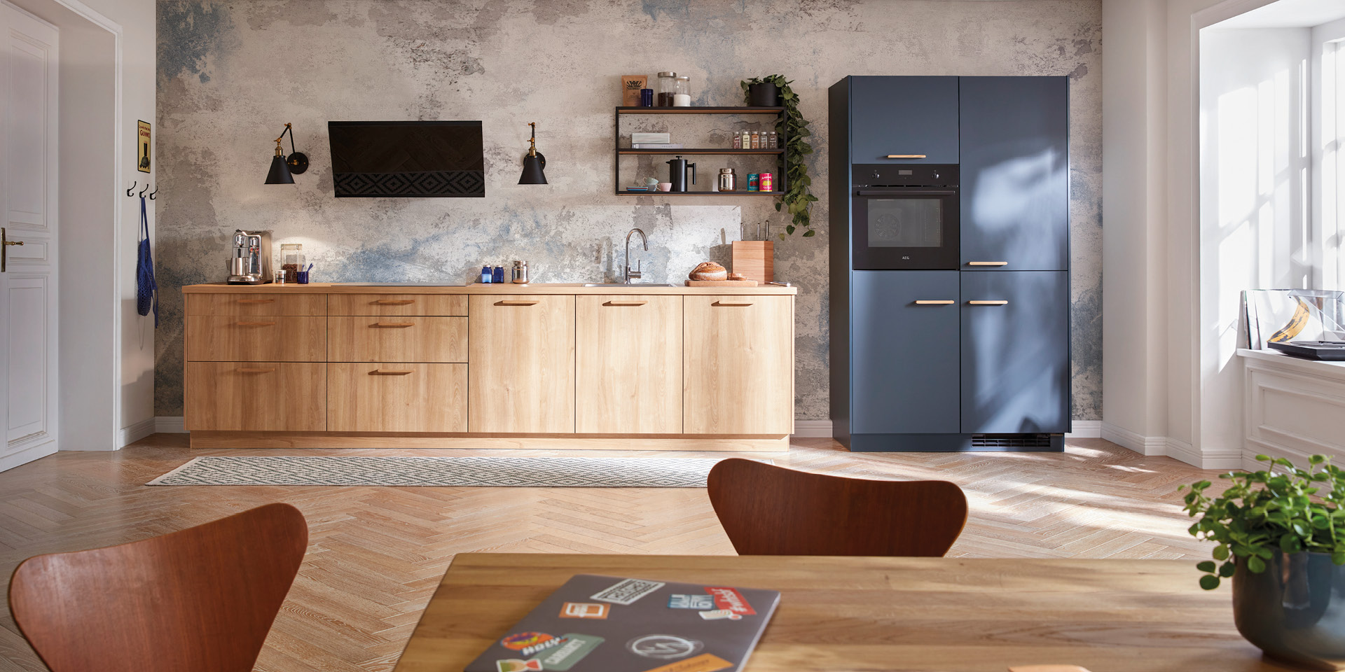 Wohnküche mit Holzzeile und blauem Hochschrank vor strukturierter Wand