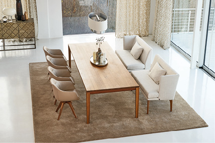 Essbereich mit Holztisch, Polsterbank und vier Stühlen auf Teppich.