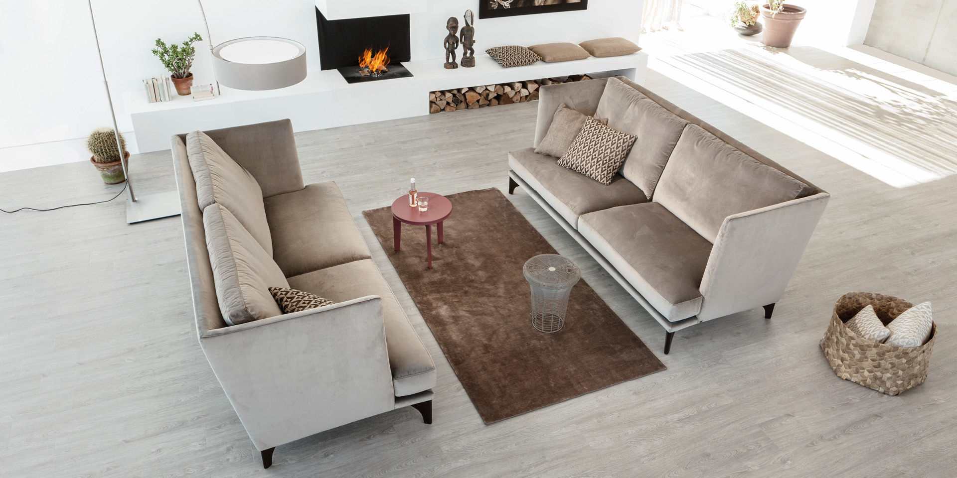 Helles Wohnzimmer mit zwei Sofas, Teppich und Kaminfeuer.