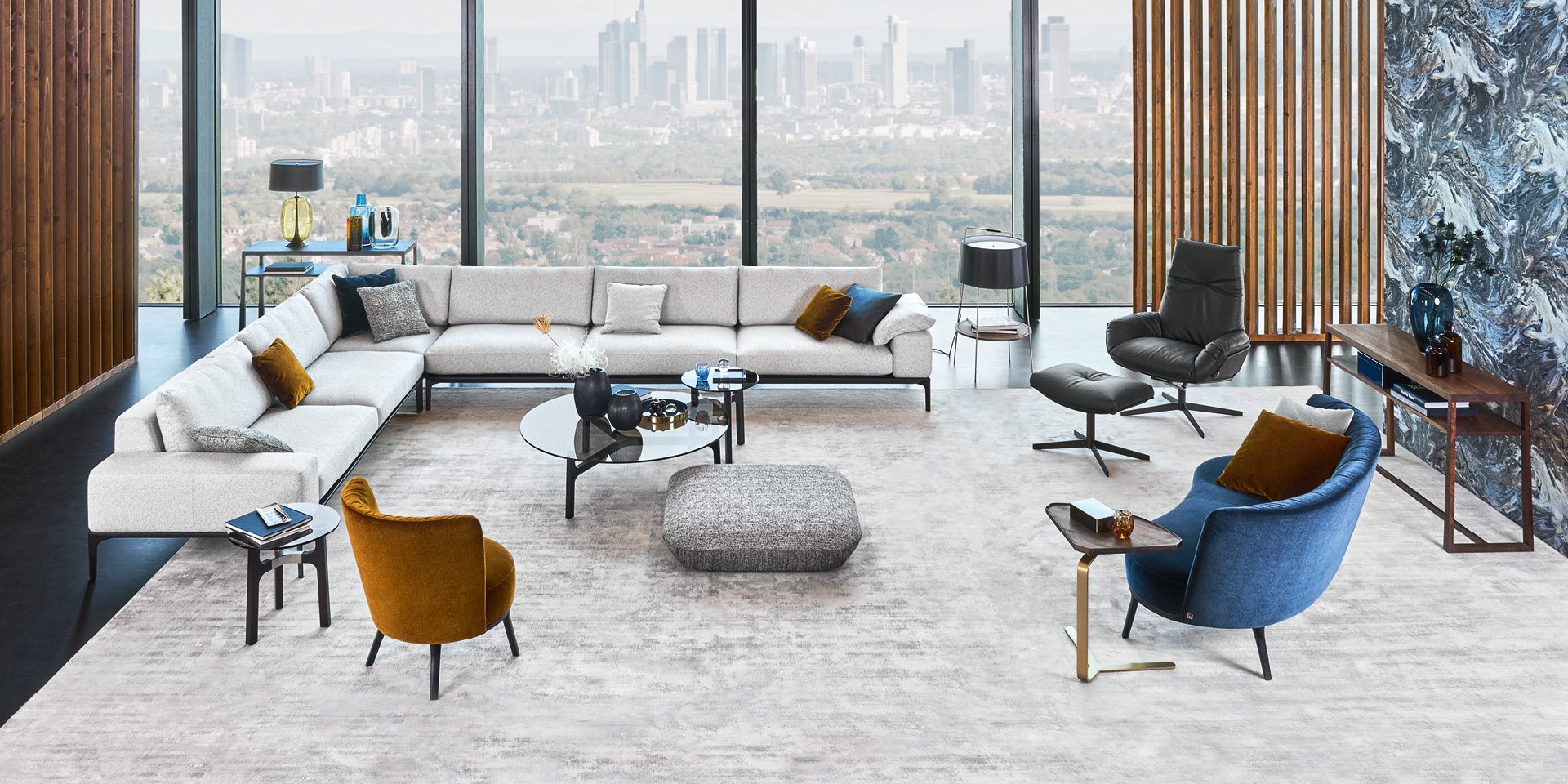 Modernes Wohnzimmer mit Ecksofa, Sesseln und Panoramafenstern mit Stadtblick.