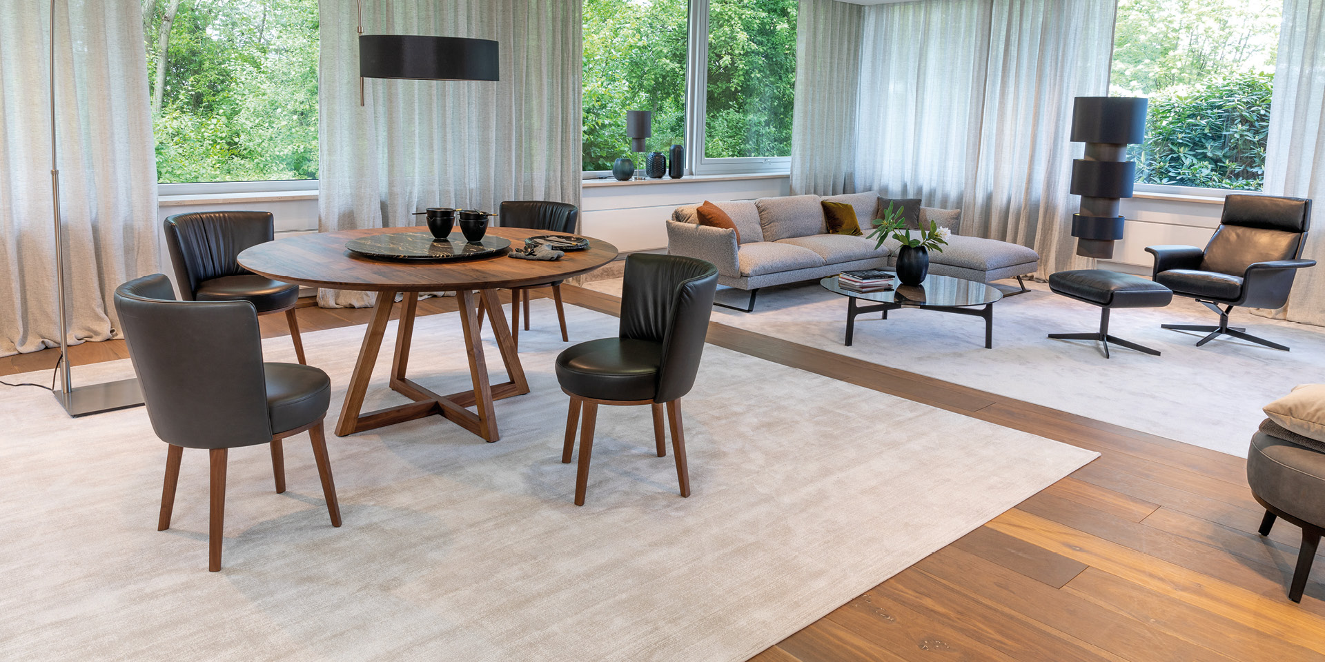 Offener Wohn-Essbereich mit Rundtisch, Stühlen, Sofa und Sessel.