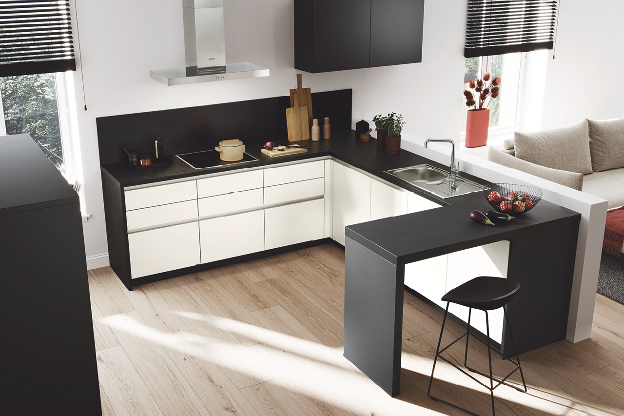 Weiße L-Küche mit schwarzer Arbeitsplatte, Spüle und Theke.