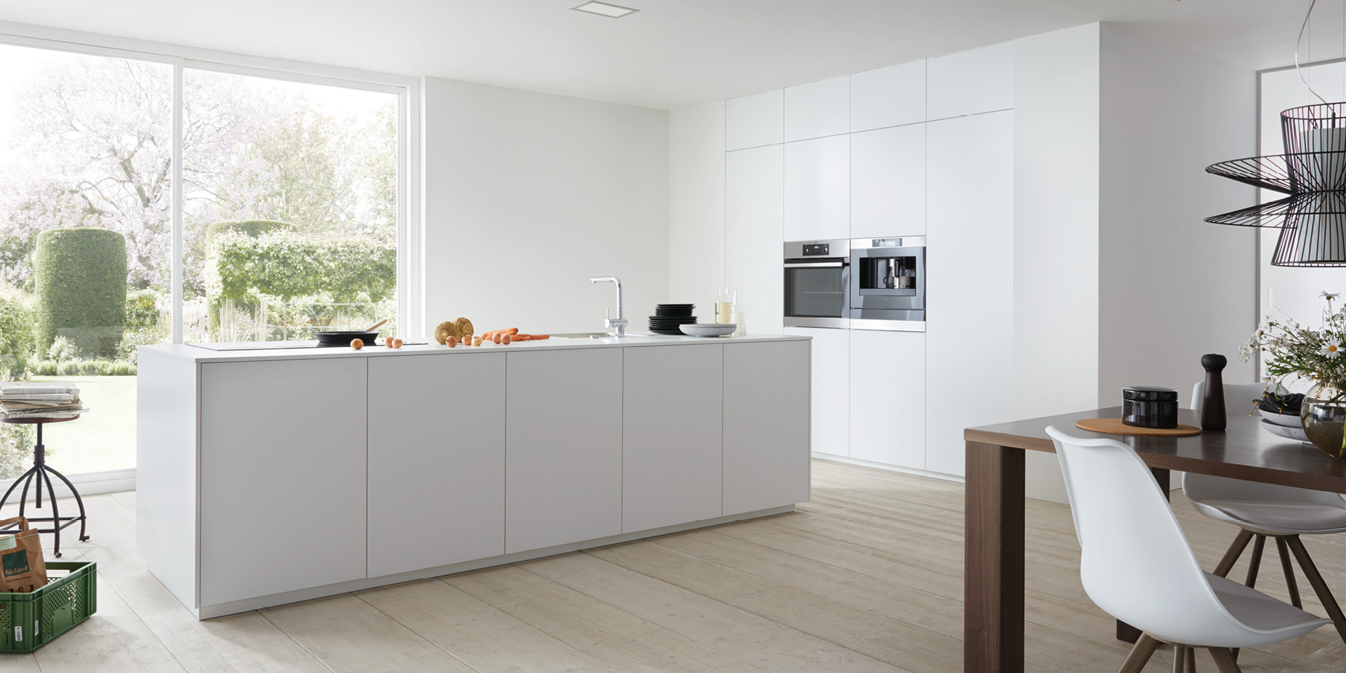 Moderne weiße Küche mit Kochinsel, Einbaugeräten und Essbereich.