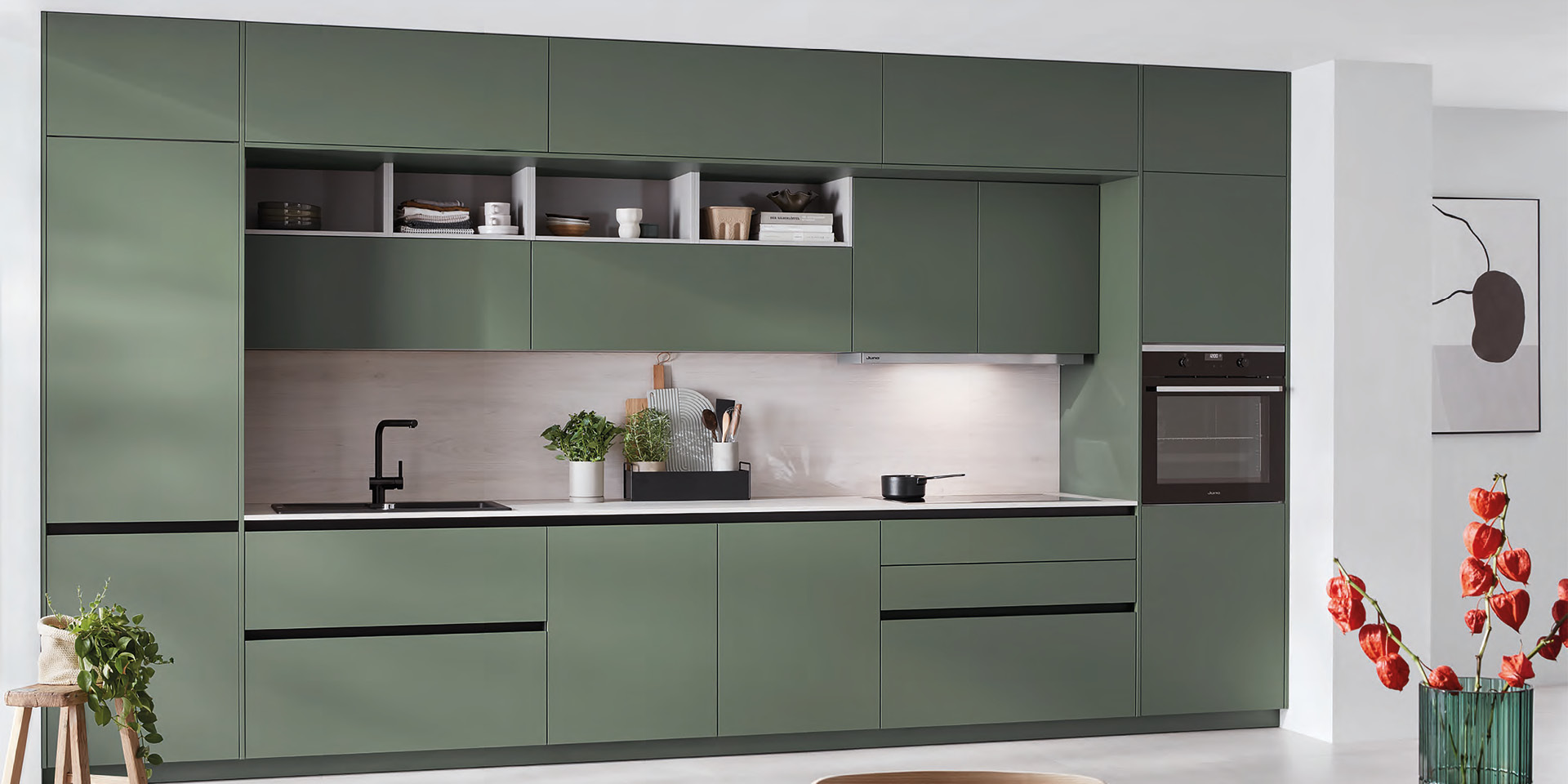 Grüne Küchenzeile mit schwarzen Akzenten, Spüle und integriertem Backofen.