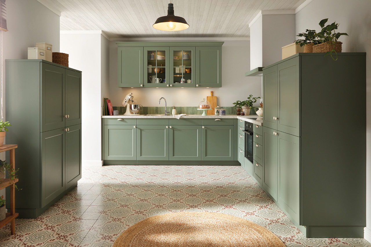 Grüne Landhausküche mit Glasoberschränken, Spüle, Backofen und Fliesenboden