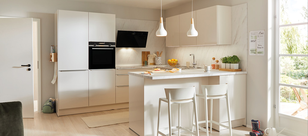 Helle Wohnküche mit Kochinsel, Barhockern, Einbaugeräten und Pendelleuchten