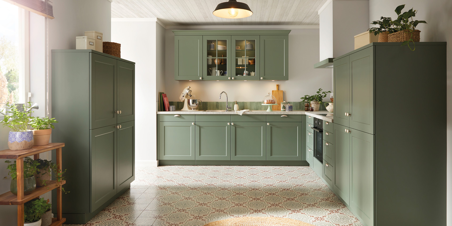 Grüne Landhausküche mit Glasoberschränken, Spüle, Backofen und Fliesenboden