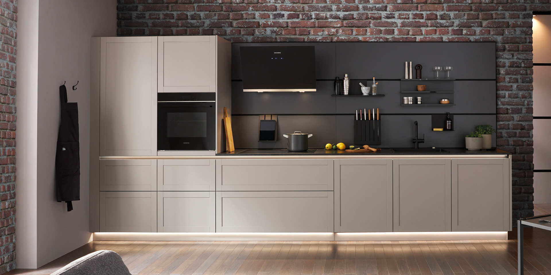 Grifflose Küchenzeile mit grauen Fronten, schwarzer Nische, Backofen, Ziegelwand