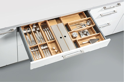 Geöffnete Küchenschublade mit Besteckeinsatz aus Holz in weißer Küche
