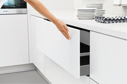 Hand öffnet grifflosen Küchenauszug in weißer Einbauküche