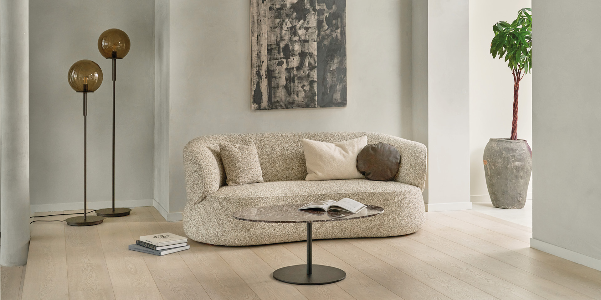 Helles Wohnzimmer mit geschwungenem Sofa, Couchtisch und Stehleuchten