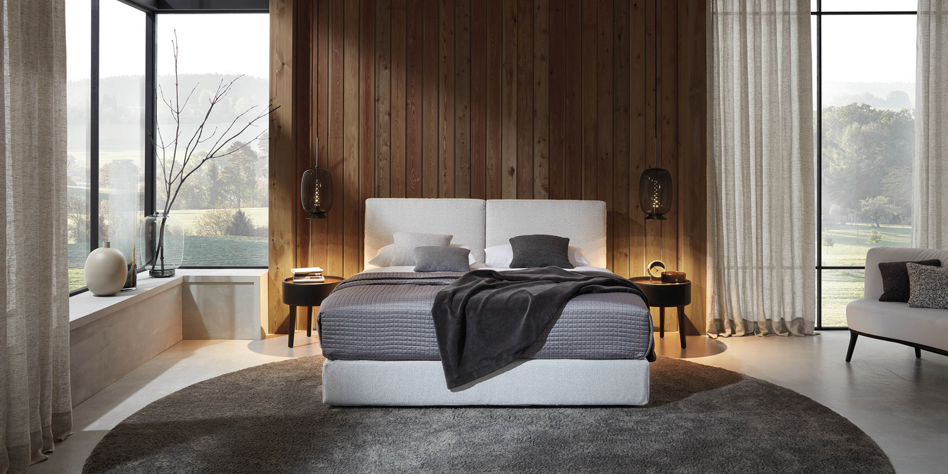 Modernes Schlafzimmer mit Polsterbett vor Holzvertäfelung und großen Fenstern