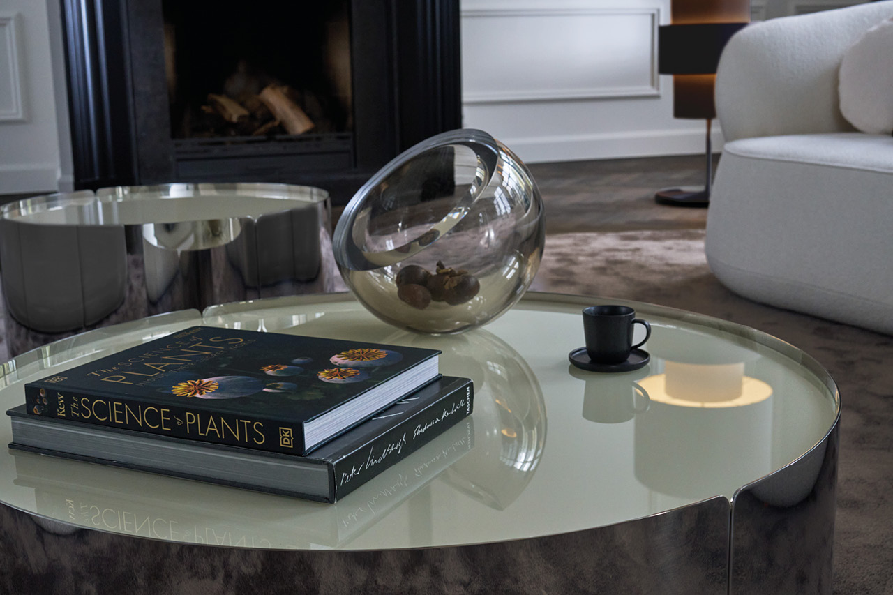 Runder Couchtisch mit Büchern, Glasschale und Tasse vor Kamin