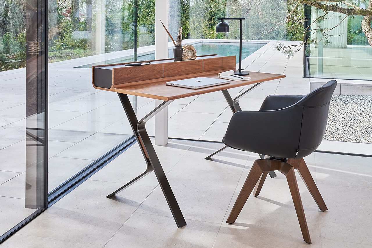 Moderner Schreibtisch aus Holz mit Sessel am Fenster, Blick ins Grüne