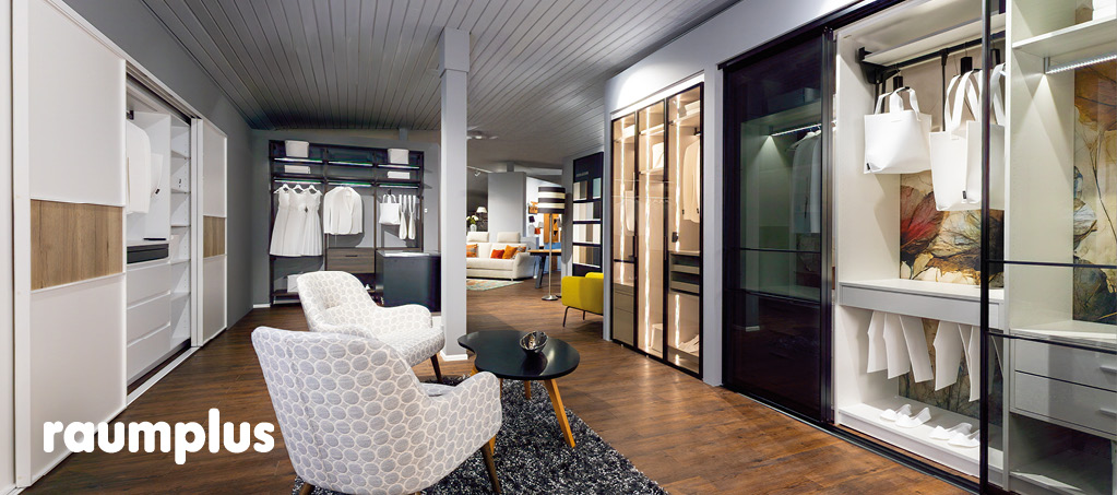 raumplus Showroom mit Schiebetürenschränken und Sitzgruppe.
