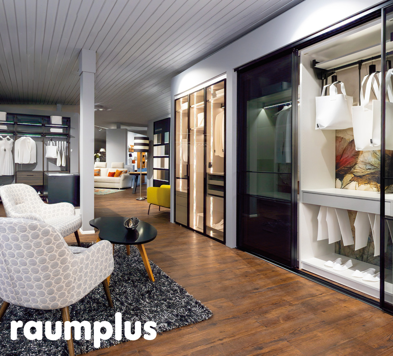 Showroom mit Schiebetürenschränken, beleuchteten Vitrinen und Sitzgruppe.
