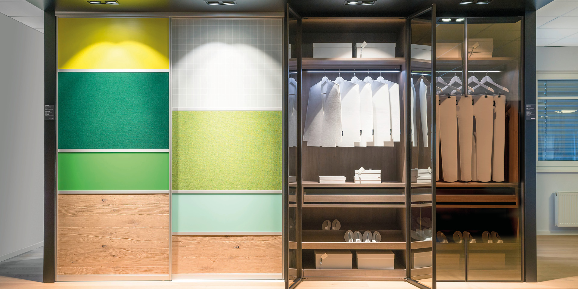 Begehbarer Kleiderschrank mit Glasfront und beleuchteter Kleiderstange.