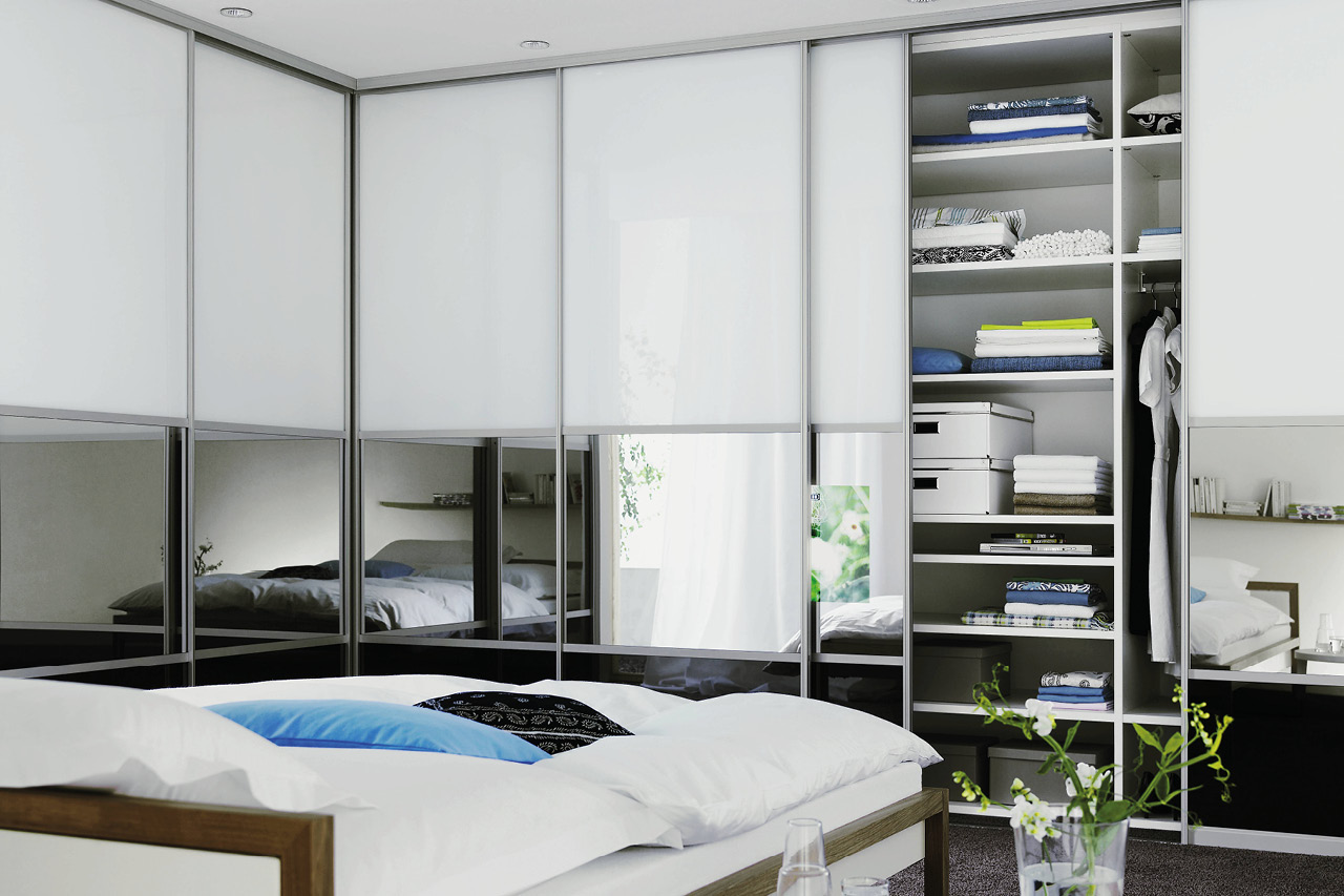 Schiebetürenschrank im Schlafzimmer, offene Sektion mit Regalen und Kleidung.