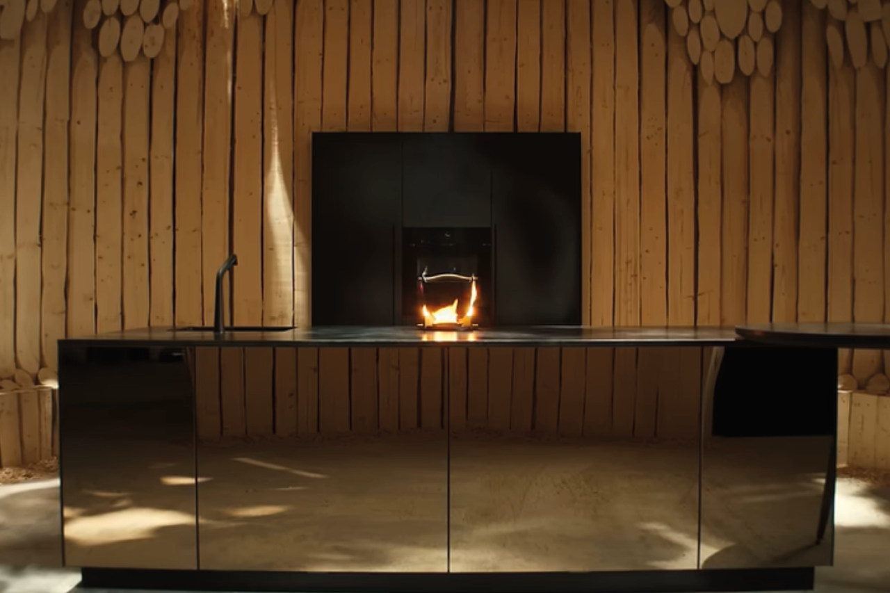 Moderne Einbauküche mit matten grünen Fronten, heller Holzarbeitsplatte und schwarzer Dunstabzugshaube. Zeitgemäßes Küchendesign mit Induktionskochfeld, schwarzer Armatur und weißen Wandfliesen im Hintergrund.