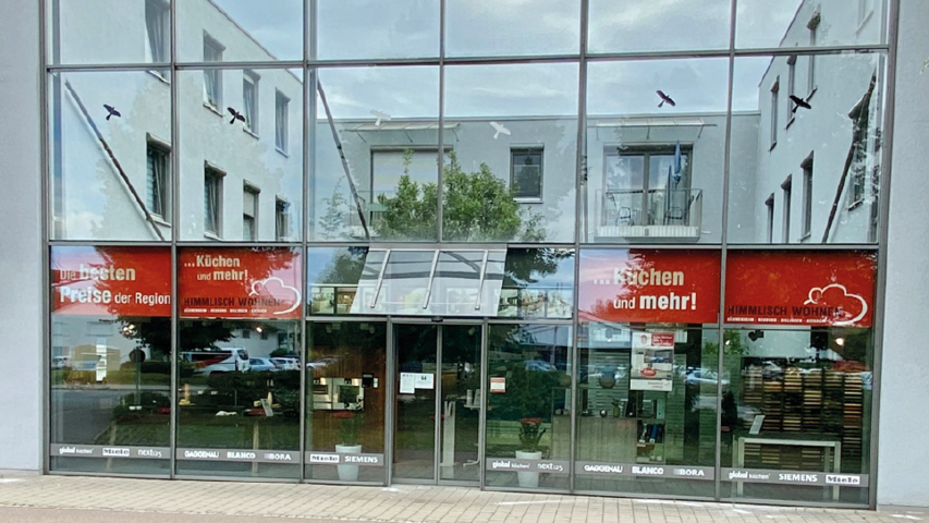 Glasfassade der Küchen Welt himmlisch wohnen in Aichach mit Einblick in moderne Küchen Ausstellung und Marken Küchengeräte für individuelle Küchenplanung