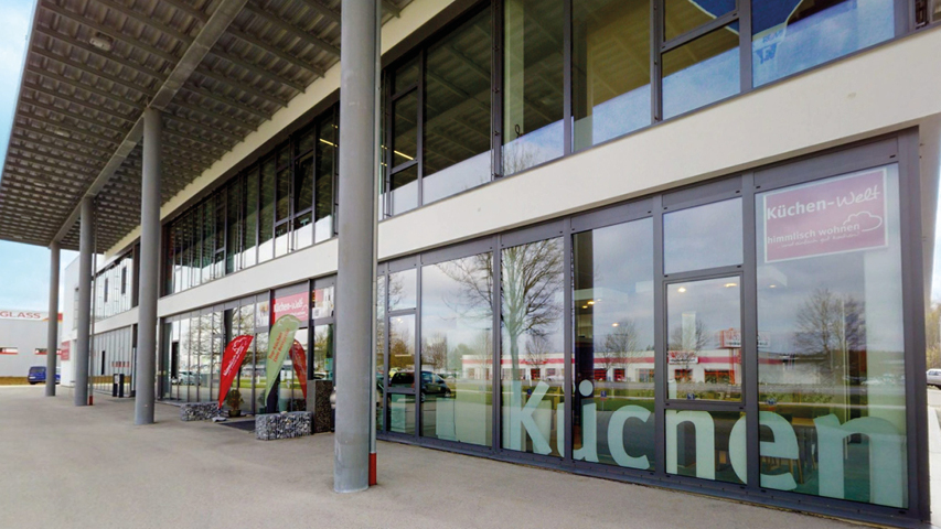 Außenansicht des Küchenstudios himmlisch wohnen in Kaufbeuren mit großen Glasfronten und Eingang zur Küchen Ausstellung für moderne Küchenplanung