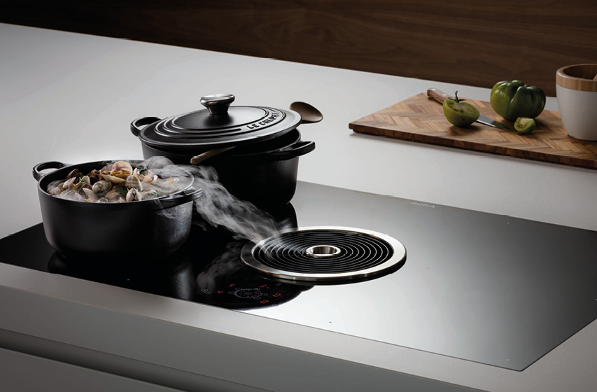 Kochfeldabzug saugt Dampf aus Topf auf moderner Kücheninsel ab