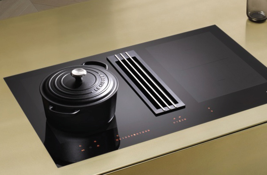 Induktionskochfeld mit integriertem Dunstabzug neben gusseisernem Topf