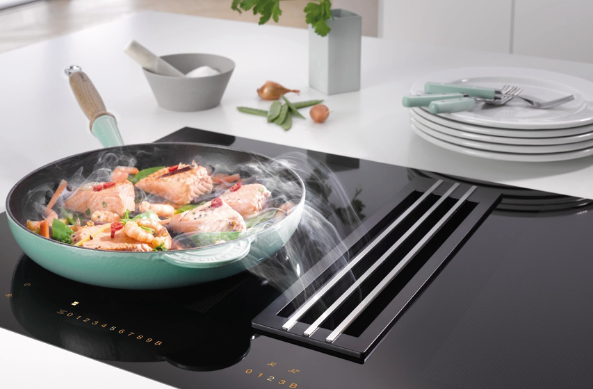 Pfanne auf Kochfeld mit integriertem Dunstabzug saugt Dampf ab