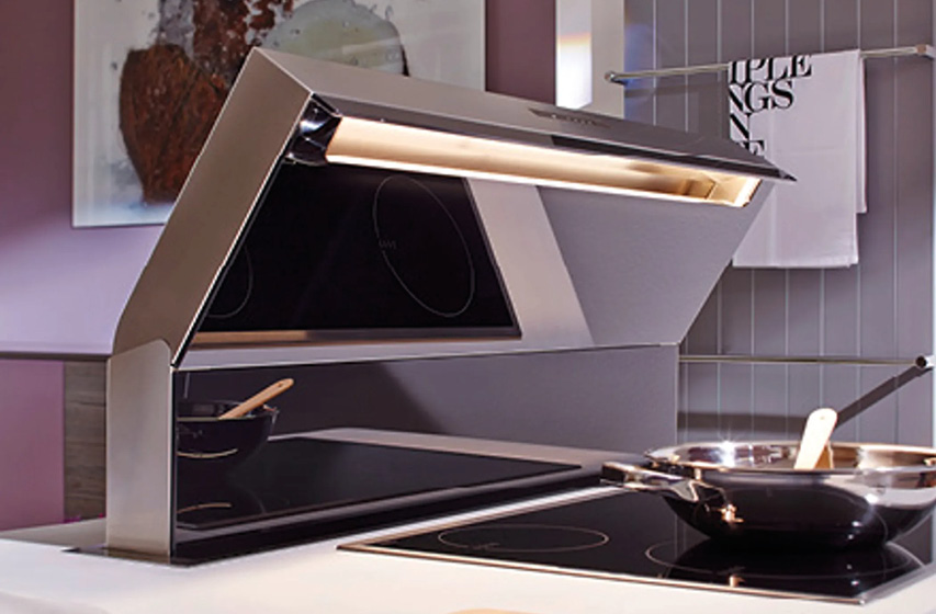 Kochfeld mit ausfahrbarem Dunstabzug neben Pfanne und Topf