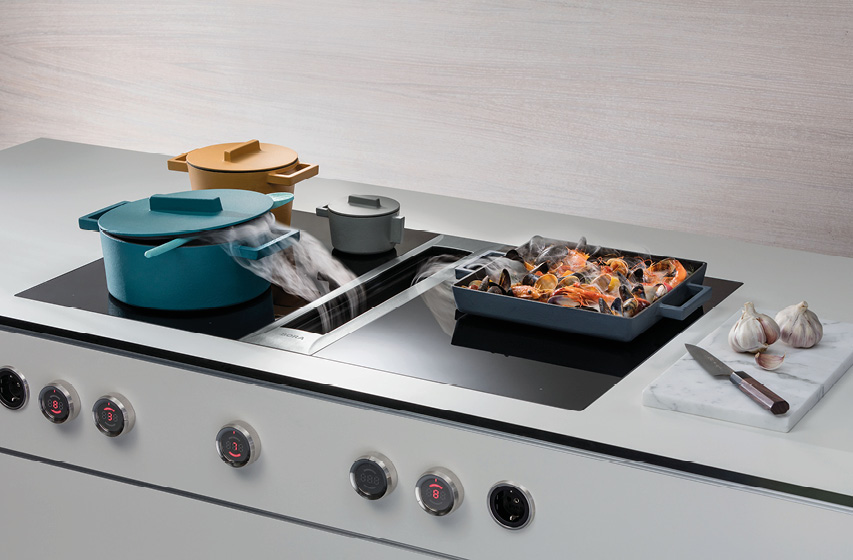 Muldenlüfter saugt Dampf zwischen Töpfen und Bräter am Kochfeld ab