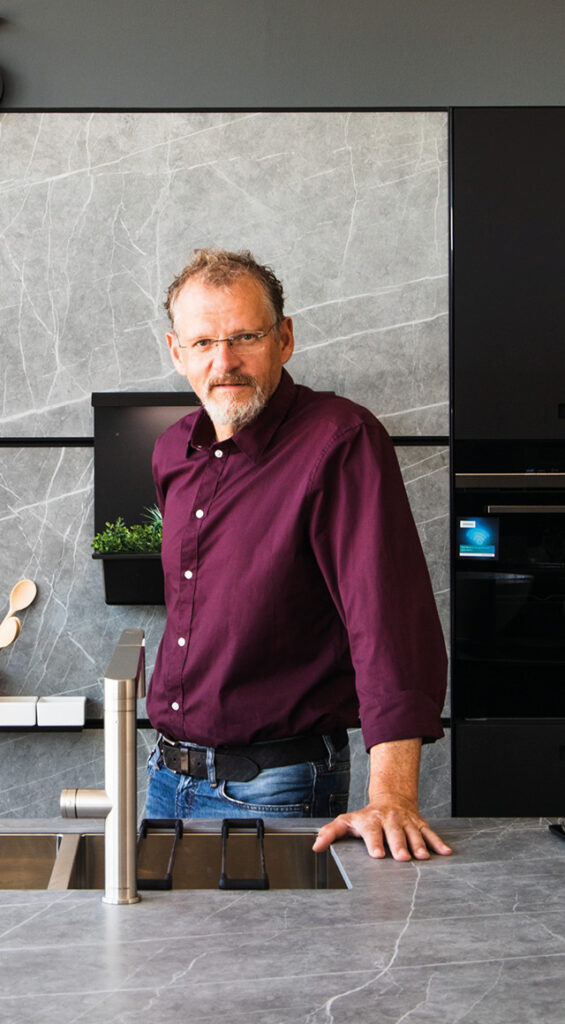 Küchenberater steht in moderner Küche mit Dunstabzug im Hintergrund