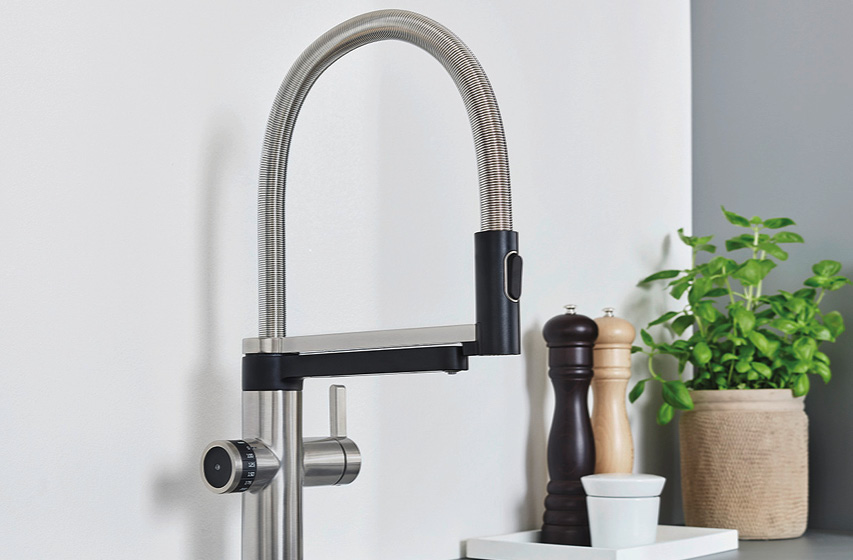 Küchenwasserhahn mit Federbogen und Brause neben Kräutertopf