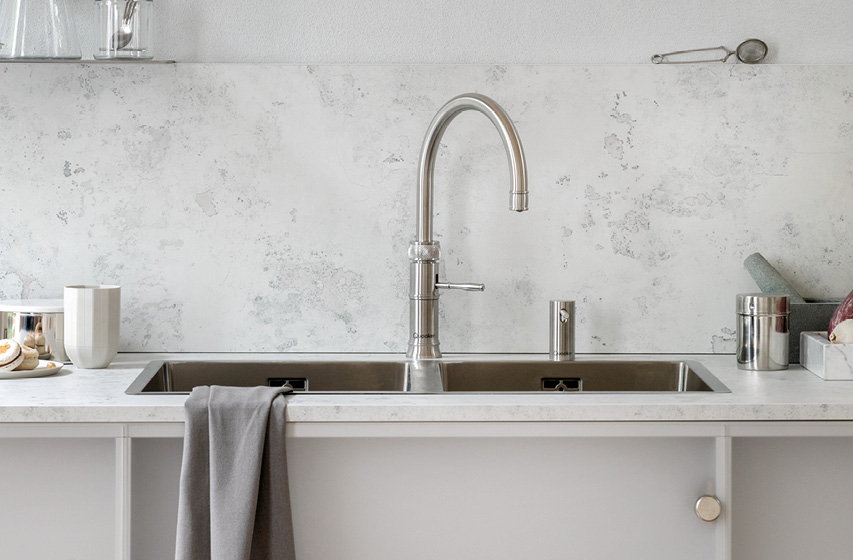 Edelstahlspüle mit hohem Küchenwasserhahn vor heller Küchenrückwand