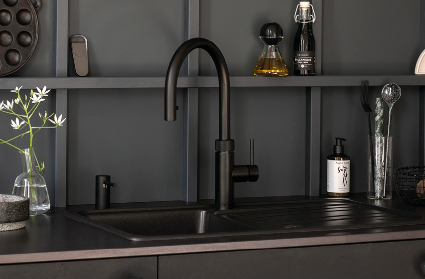 Schwarzer Küchenwasserhahn über dunkler Spüle mit Abtropffläche