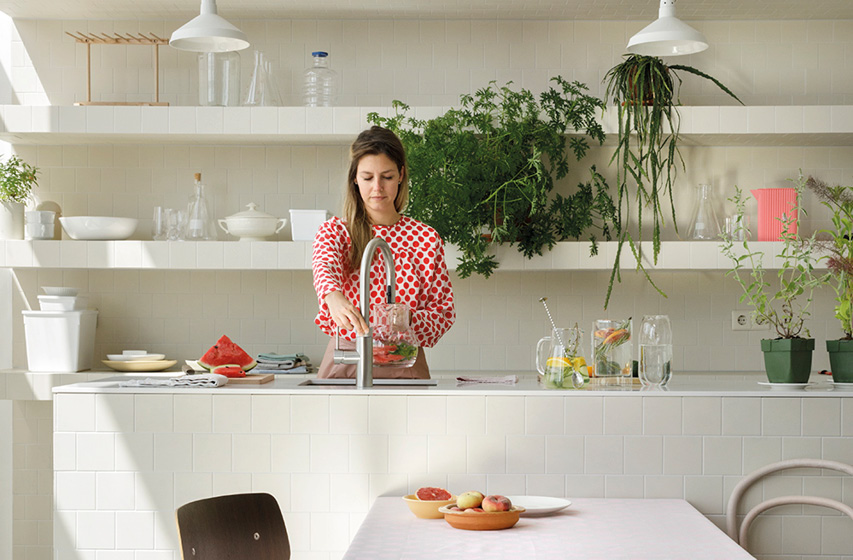 Person spült Obst am hohen Küchenwasserhahn in heller Küche