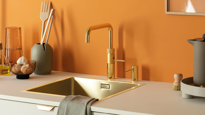 Goldener Wasserhahn und goldene Spüle in moderner Küche