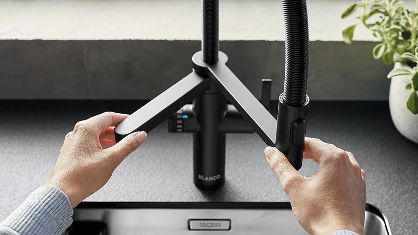 Hände bedienen Küchenarmatur mit zwei Ausläufen über Spüle