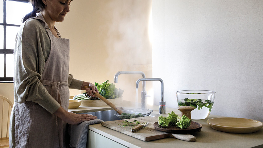Person bereitet Gemüse an Spüle mit zwei Küchenarmaturen vor