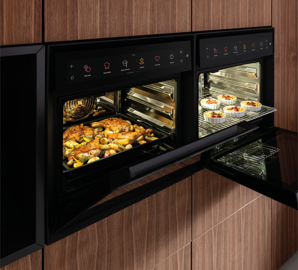 Zwei Dampfbacköfen mit geöffneten Türen und Speisen auf Blechen