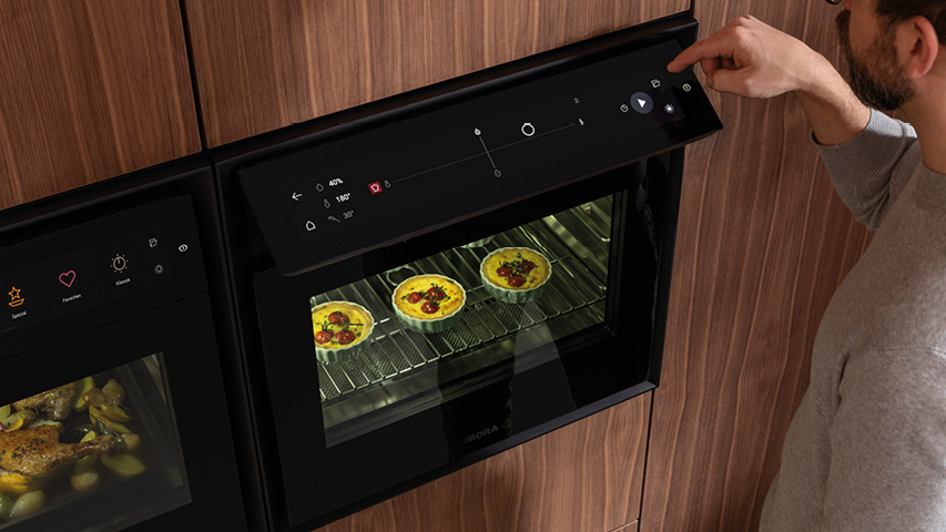 Person bedient Dampfbackofen-Touchdisplay, Tartes backen im Garraum
