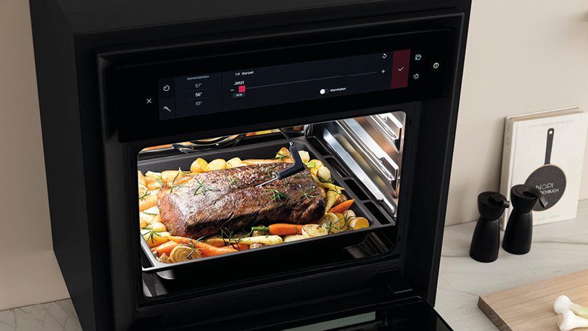 Dampfbackofen mit Braten und Gemüse auf herausgezogenem Backblech