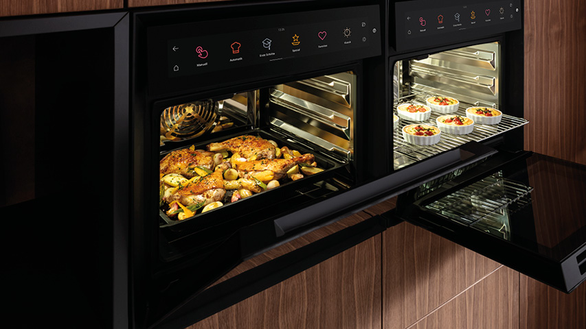 Zwei geöffnete Dampfbacköfen, Hähnchenblech und kleine Aufläufe im Garraum