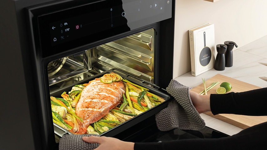 Dampfbackofen mit Lachs und Gemüse auf herausgezogenem Backblech