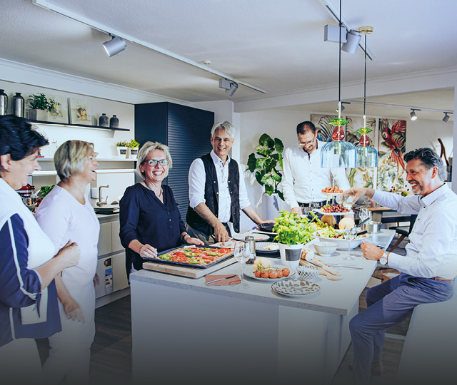 Gruppe im Küchenstudio an Kochinsel, Link zu Filialen