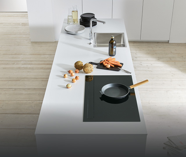 Helle Küchenarbeitsplatte mit Spüle, Kochfeld und Zutaten, Teaserlink