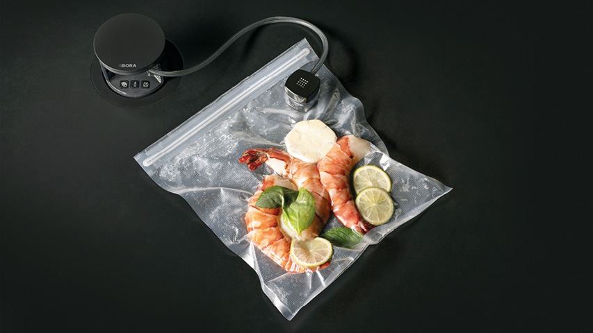 Vakuumiergerät mit Beutel, Garnelen und Limettenscheiben
