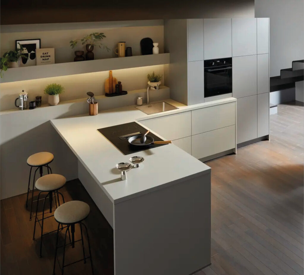 Kücheninsel mit Kochfeld, Barhockern und integrierter Spüle in Wohnküche.