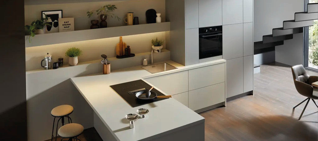 Kücheninsel mit Kochfeld, Barhockern und integrierter Spüle in Wohnküche.